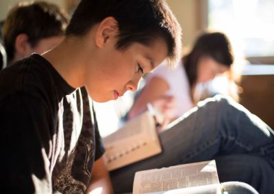 Young boy reading scriptures with family